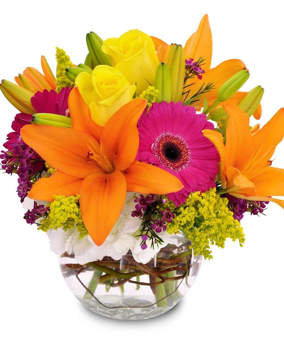 Orange lilies, pink daisies and other bright flowers in a glass bowl vase.